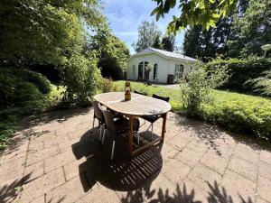 a wooden table with two chairs and a bottle of beer at Villaatje Veluwe in Garderen