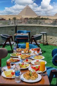 a table with plates of food with the pyramids in the background at Happy View INN in Giza