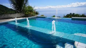 a swimming pool with two fountains in the water at Oceano con Vista Mountain Resort in Tagbaobo