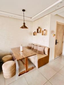 a dining room with a wooden table and a couch at Appartement Cozy avec piscine in Sidi Rahal