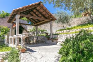 a stone pergola with a wooden roof on a patio at Apartments with parking space Sutivan, Brac - 2846 in Sutivan