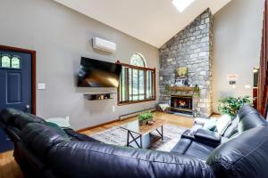 a living room with a leather couch and a stone fireplace at Lake Access & Private Hot Tub at Poconos Home! in White Haven