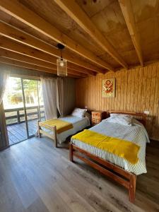two beds in a room with wooden walls at Cabaña en Rafael in Tomé
