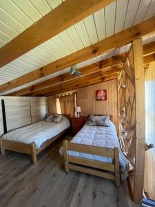 two beds in a room with wooden ceilings at Cabaña en Rafael in Tomé