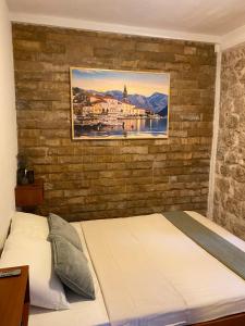 a bed in a bedroom with a brick wall at Charming Stone Cottage Kotor in Kotor