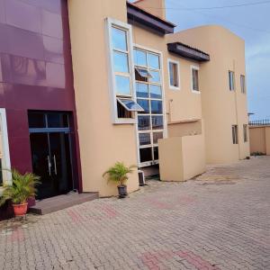 a building with two potted plants in front of it at Posh Hotelia in Hausa