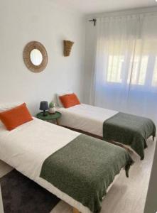 two beds in a white room with a mirror at Casa da Matilde in Estoril
