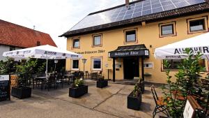 a restaurant with tables and umbrellas in front of a building at Gasthaus Schwarzer Adler in Holzgünz
