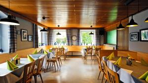 a dining room with tables and chairs and windows at Gasthaus Schwarzer Adler in Holzgünz