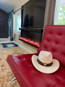 a cowboy hat sitting on a red couch with a fireplace at Sip and Soak, hotel-style room in Calgary