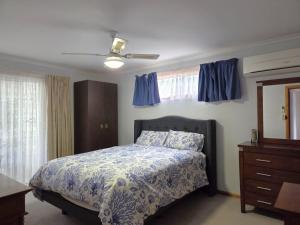 a bedroom with a bed and a dresser and blue curtains at Dolphin Cove in Wallaroo
