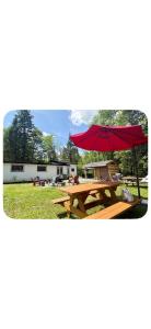 a picnic table with a red umbrella in a field at Chalet Havana in Namur