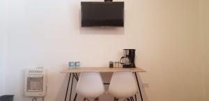a table with two white chairs and a tv on a wall at Cabaña La Camelia in Creel