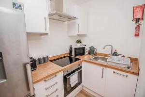 a small kitchen with white cabinets and a sink at City Centre Apt with FREE PARKING in Doncaster