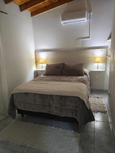 a bedroom with a large bed in a room with two lamps at Quimey Ruca Alojamientos in Neuquén