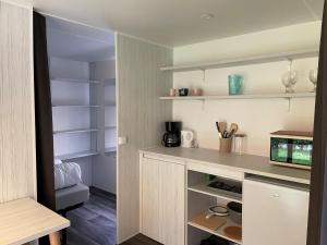 a kitchen with white shelves and a counter at Cozy Coco Sweet Glamping Tent for 4 in Rijkevorsel
