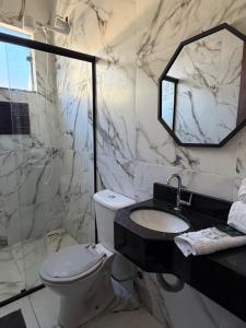 ein Badezimmer mit Toilette, Waschbecken und Spiegel in der Unterkunft Hotel Pousada Colliseu in Aparecida