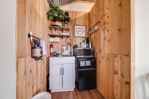 a kitchen with wooden walls and a black refrigerator at Hill Country Cabin 4 in Canyon Lake