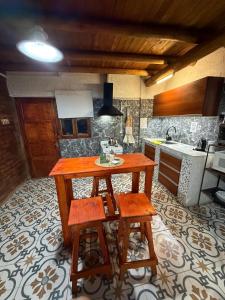 a kitchen with a wooden table and two stools at Alojamiento en Barreal, San Juan in Barreal