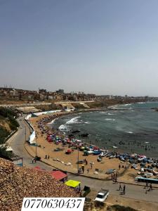 a beach with a lot of people and umbrellas at مستغانم حي السلام المجدوب in Sidi Mohammed Medjoub