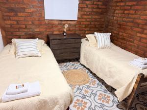 two beds in a room with a brick wall at Alojamiento en Barreal, San Juan in Barreal +7 photos