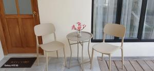three chairs and a table with a vase of flowers on it at Kooka Residence Surabaya in Surabaya