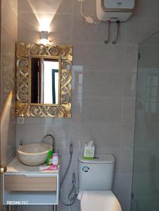a bathroom with a sink and a toilet and a mirror at Kooka Residence Surabaya in Surabaya