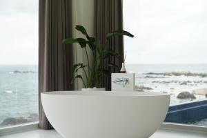 a white tub in front of a window with a plant at Pohang Horizon Poolvilla in Pohang