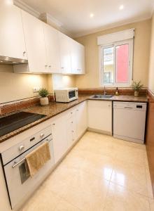a kitchen with white cabinets and a sink and a microwave at Raffaelas vacation apartment in Torrevieja