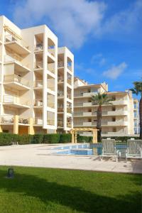 a large apartment building with a pool and two chairs at Ver o Mar in Albufeira