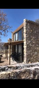 a stone house with a wooden porch and benches at Velas del Lago in Piedras Moradas