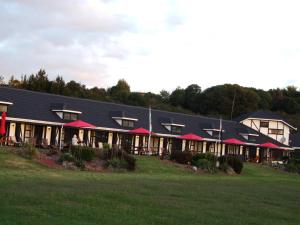 Un edificio con techos rojos y un campo de césped. en Chelmswood Motel Taupo, en Taupo