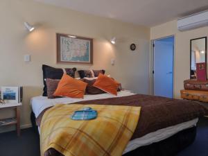 a bedroom with a large bed with orange pillows at #6 Glenorchy Alpine Suite in Glenorchy