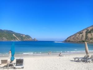 a beach with chairs and umbrellas and people on it at Bale Sasak guest house in Selaparang