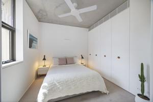 a white bedroom with a bed and a ceiling fan at Modern Beach Ocean View 1 BDR Parking Balcony AC in Sydney +17 photos