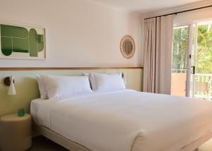 a bedroom with a large white bed and a window at The Roy in Rainbow Beach