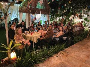 a group of people sitting around a table in a garden at Casa Valldemossa in Búzios
