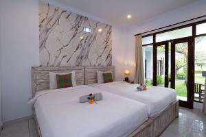a bedroom with two beds with white sheets at Ayu Shanti Guest House Ubud in Ubud