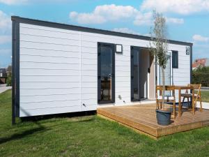 a small white tiny house with a wooden deck at Caravan Bredene by the sea in Bredene +17 photos