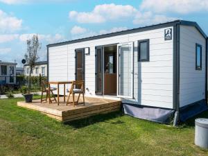 a small white tiny house with a wooden deck at Caravan Bredene by the sea in Bredene