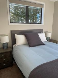 a bedroom with a bed with two lamps and a window at Whakatā in Te Anau +37 photos