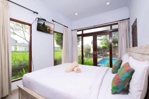 a bedroom with a white bed and a large window at Ayu Shanti Guest House Ubud in Ubud