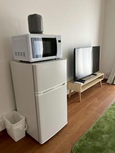 a microwave and a tv on top of a refrigerator at Arch Garden in Ishihara