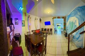 a dining room with a painting of a wave on the wall at Bouganvile Hostel Ilha Grande in Abraão