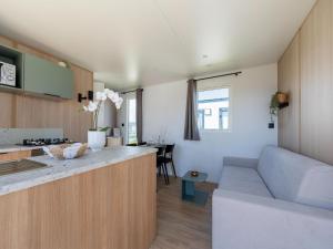 a kitchen and living room with a couch and a table at Caravan Bredene on the coast in Bredene