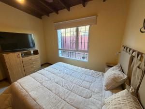 a bedroom with a bed and a tv and a window at Refugio serrano in Tandil