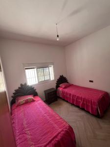 two beds in a room with red sheets at La Vista Azul in Belyounech 