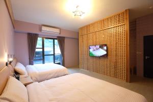 花蓮市にあるHualien Shiado B&Bのベッドルーム1室(ベッド2台、壁にテレビ付)