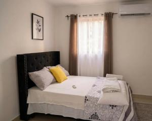 a bedroom with a bed with yellow pillows and a window at Villa renacer 1 in Baní
