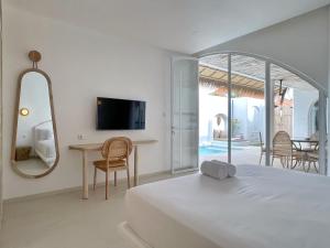a bedroom with a bed and a table and a tv at Villa Sei Uluwatu by LODGELINK BALI in Uluwatu +38 photos